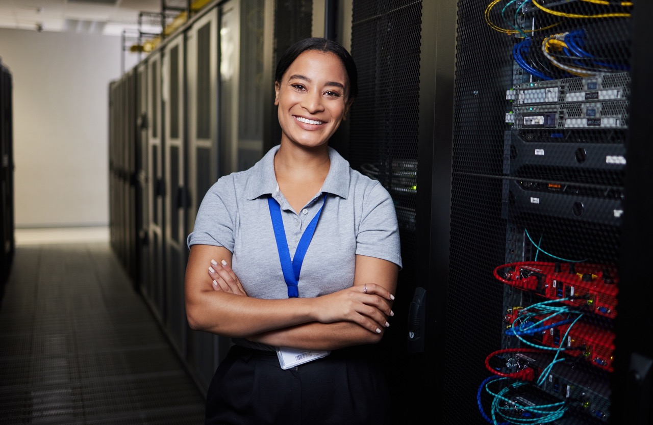Woman with arms crossed smiling in front of server system