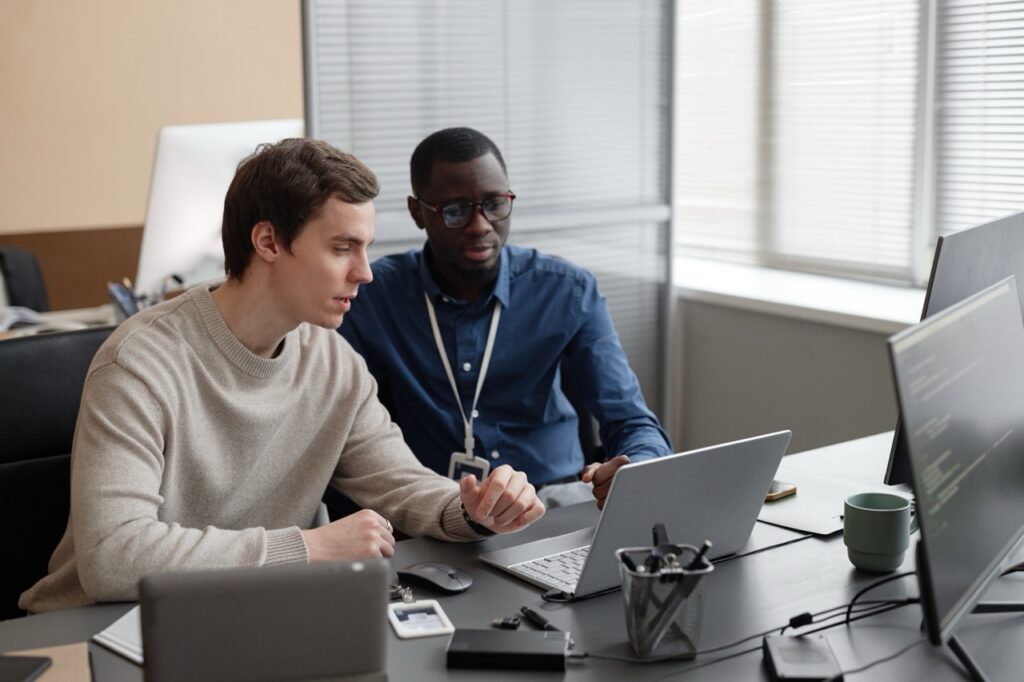 Two men sitting at desk looking at screen