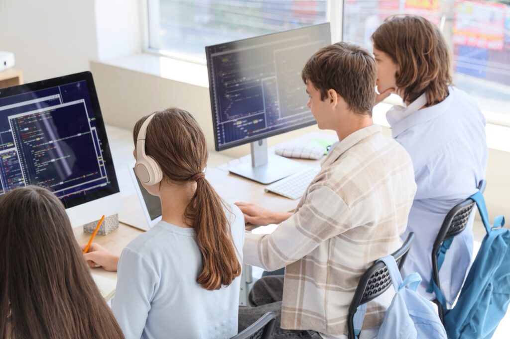 Students sitting in front of screen with code displayed